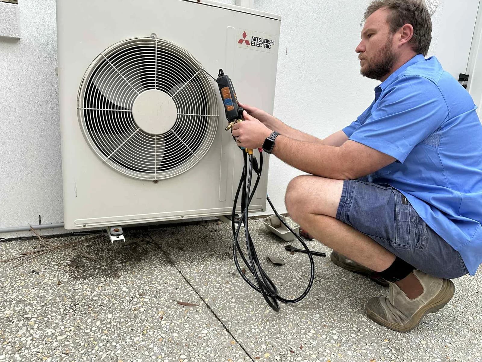 A Coola technician servicing an outdoor air-conditioning condenser at a Brisbane home