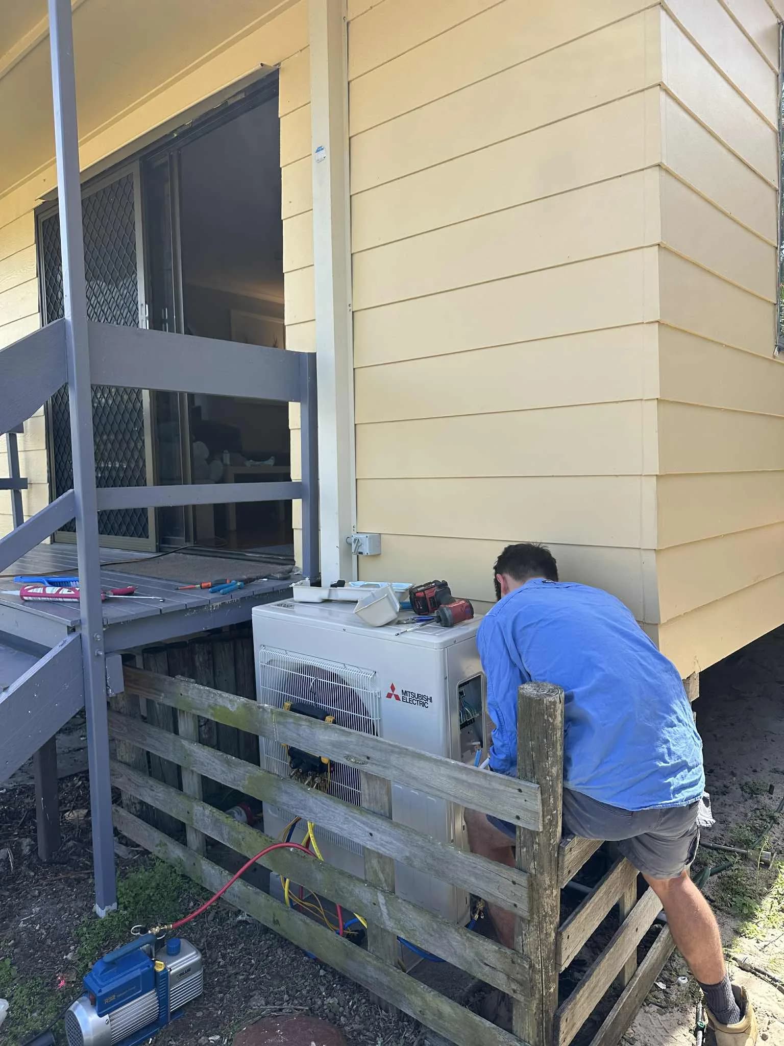 A Coola technician installing a Mitsubishi Electric outdoor condenser at a Brisbane home
