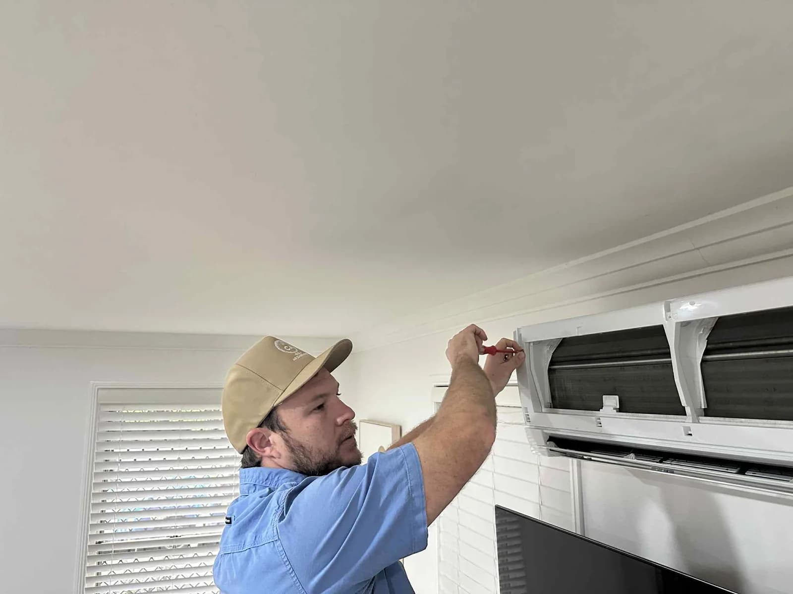 A Coola technician fitting a wall-mounted split-system head indoors