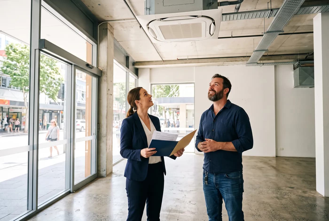 A property manager and a tenant looking at a ceiling cassette air conditioner in an empty commercial tenancy